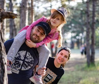 A joyful family enjoying a playful day in a sunlit forest park, capturing the essence of togetherness.