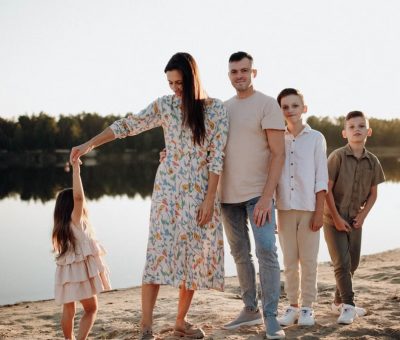 A family of five enjoys a serene lakeside vacation at sunset, capturing precious moments together.